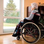 Seniorin im Rollstuhl schaut aus dem Fenster