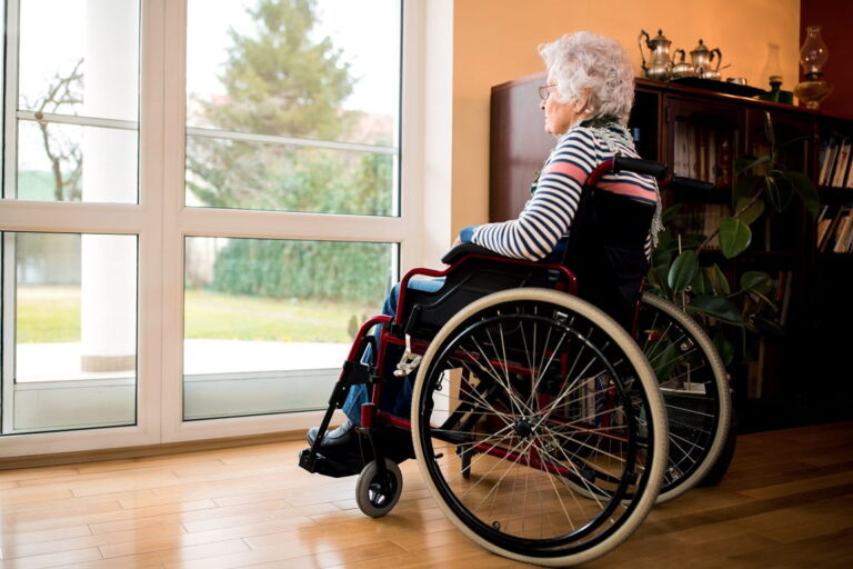 Seniorin im Rollstuhl schaut aus dem Fenster