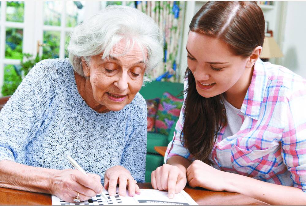 Seniorin und Betreuerin lösen gemeinsam Kreuzworträtsel