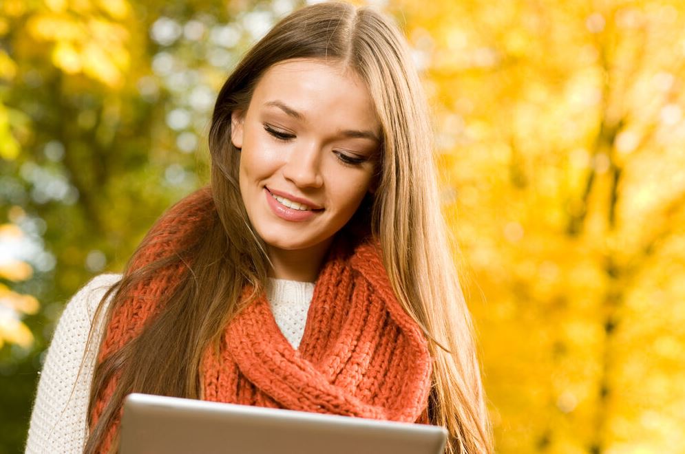 Junge Frau am PC/Tablet draußen im Herbst, AdobeStock/Shestakoff