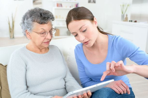 Seniorin und Betreuerin surfen im Internet mit einem Tablet